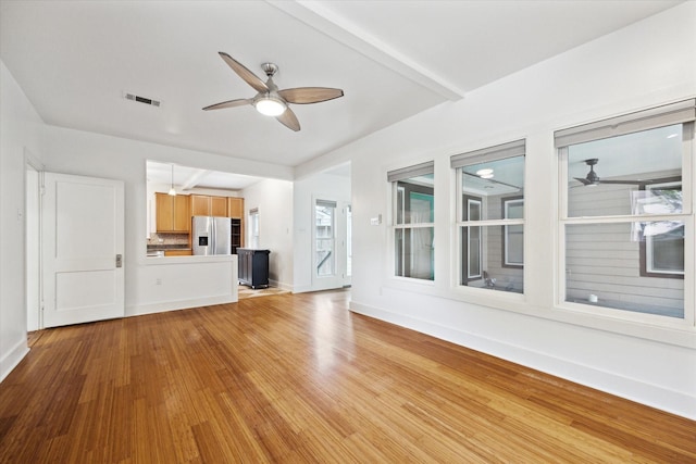 924 E 27th St, Houston, TX 77009 - unfurnished living room with a ceiling fan, light wood-style floors, baseboards, and plenty of natural light