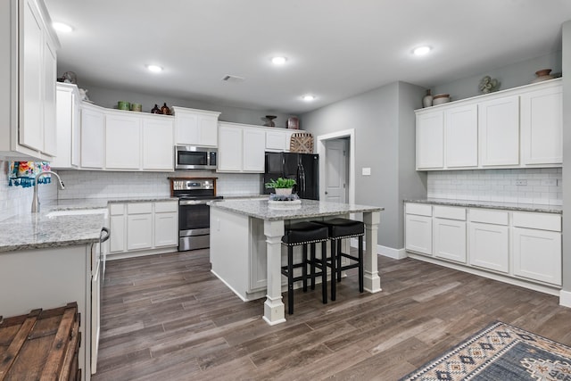 8729 Nathan Dr, Waller, TX 77484 - kitchen with appliances with stainless steel finishes, a sink, backsplash, white cabinetry, and a kitchen island