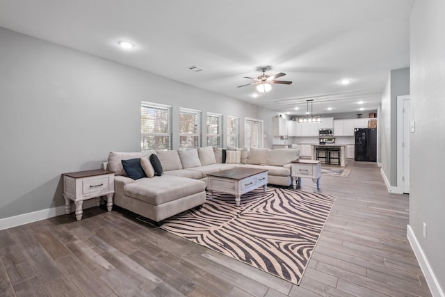 8729 Nathan Dr, Waller, TX 77484 - living room featuring ceiling fan, baseboards, light wood-style floors, recessed lighting, and a chandelier