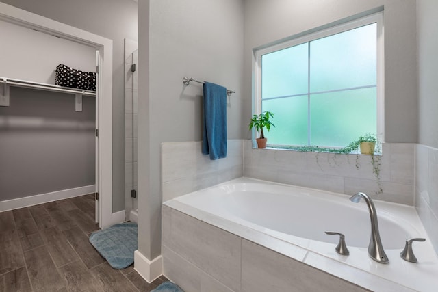 8729 Nathan Dr, Waller, TX 77484 - bathroom featuring a stall shower, a spacious closet, a bath, wood finished floors, and baseboards