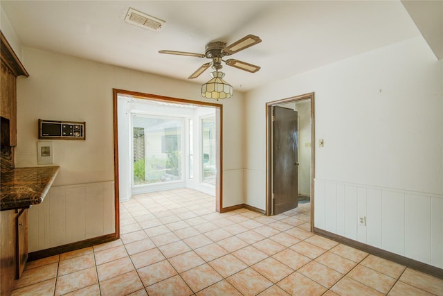 5211 Olympia Fields Ln, Houston, TX 77069 - unfurnished dining area with a ceiling fan, a wainscoted wall, and light tile patterned floors