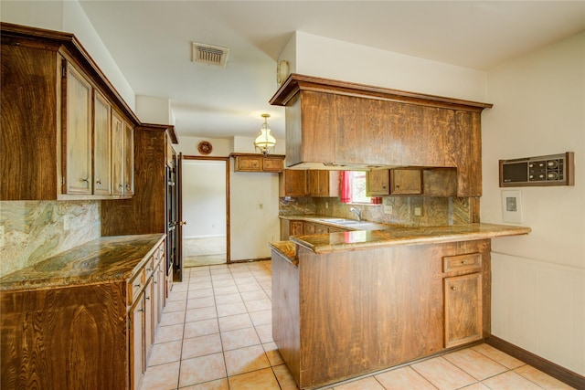 5211 Olympia Fields Ln, Houston, TX 77069 - kitchen featuring a peninsula, light tile patterned flooring, backsplash, a sink, and a wainscoted wall