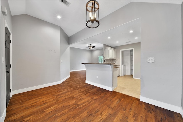 kitchen featuring vaulted ceiling, dark countertops, ceiling fan, white cabinets, and wood finished floors