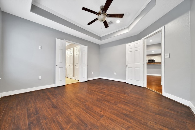unfurnished bedroom featuring a raised ceiling, wood finished floors, baseboards, ornamental molding, and recessed lighting