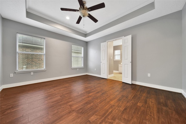 unfurnished bedroom featuring a raised ceiling, wood finished floors, crown molding, baseboards, and recessed lighting