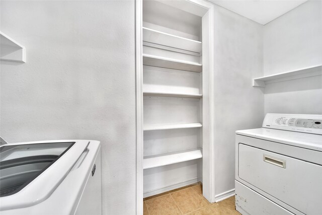 clothes washing area featuring washer and dryer and light tile patterned flooring