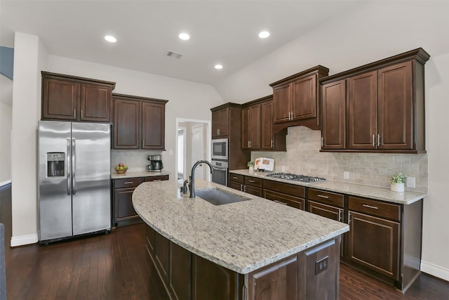16819 Big Reed Dr, Humble, TX 77346 - kitchen with stainless steel appliances, a sink, dark wood finished floors, dark brown cabinetry, and a kitchen island with sink