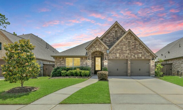 16819 Big Reed Dr, Humble, TX 77346 - french country home featuring brick siding, concrete driveway, an attached garage, roof with shingles, and a gate