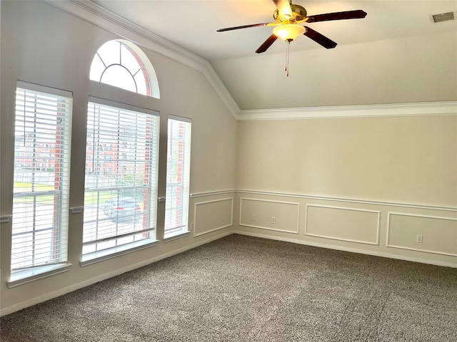 unfurnished room featuring plenty of natural light, lofted ceiling, dark colored carpet, ornamental molding, and a ceiling fan
