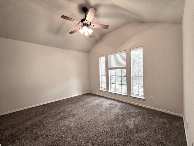 unfurnished room featuring vaulted ceiling, dark colored carpet, ceiling fan, and baseboards