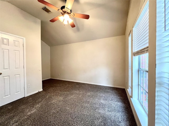 additional living space featuring lofted ceiling, plenty of natural light, dark colored carpet, and a ceiling fan
