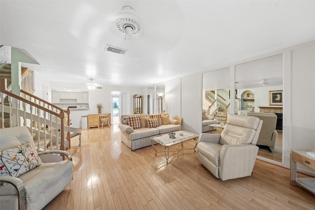14911 Wunderlich Dr Unit 1501, Houston, TX 77069 - living area featuring stairs, ceiling fan, light wood-style flooring, and a tile fireplace