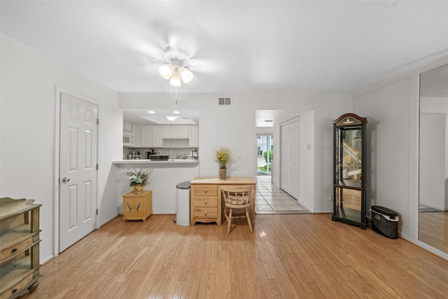 14911 Wunderlich Dr Unit 1501, Houston, TX 77069 - kitchen featuring light wood-style floors, white cabinetry, a ceiling fan, white microwave, and a peninsula