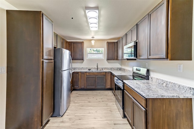 401 S Fig St, Sweeny, TX 77480 - kitchen with stainless steel appliances, a sink, light wood-type flooring, and light stone counters