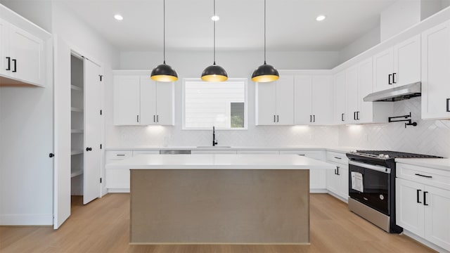 3605 Mount Pleasant St, Houston, TX 77021 - kitchen featuring stainless steel range with gas cooktop, under cabinet range hood, light wood-style floors, a sink, and backsplash