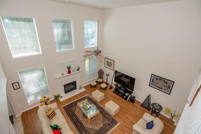 20018 Rene Creek Ct, Spring, TX 77388 - living room with a premium fireplace, a ceiling fan, baseboards, wood finished floors, and a high ceiling