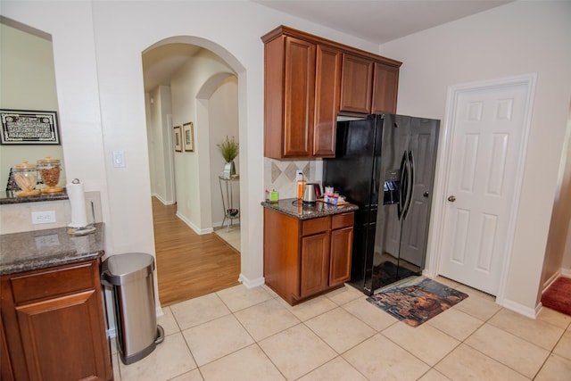 20018 Rene Creek Ct, Spring, TX 77388 - kitchen featuring black fridge, arched walkways, decorative backsplash, and dark stone countertops