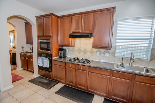 20018 Rene Creek Ct, Spring, TX 77388 - kitchen with black appliances, a sink, under cabinet range hood, arched walkways, and decorative backsplash
