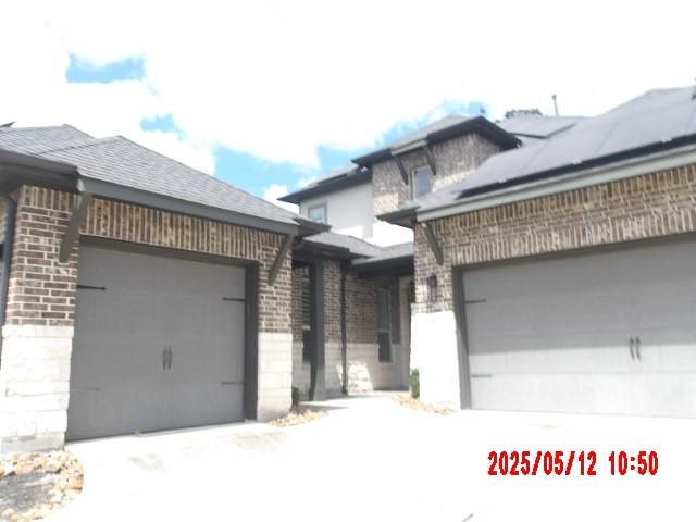 3817 Hawthorn Shadow Ct, Spring, TX 77386 - view of front of house with brick siding, a garage, driveway, and roof mounted solar panels