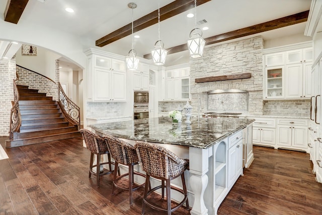 6206 Terwilliger Way, Houston, TX 77057 - kitchen featuring stainless steel oven, beam ceiling, decorative backsplash, a center island, and arched walkways
