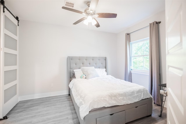 12422 Texas Army Trl, Cypress, TX 77429 - bedroom featuring a barn door, wood finished floors, baseboards, and a ceiling fan