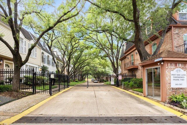 495 N Post Oak Ln, Houston, TX 77024 - view of concrete road with a gate, a gated entry, curbs, and a residential view