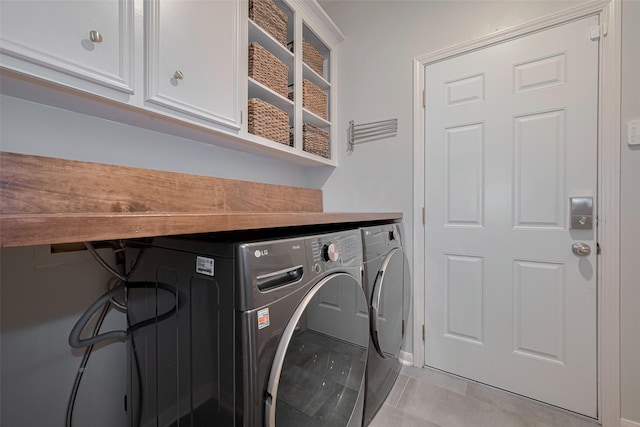 12438 Piping Rock Dr, Houston, TX 77077 - laundry room featuring washing machine and clothes dryer, cabinet space, light tile patterned floors, and baseboards
