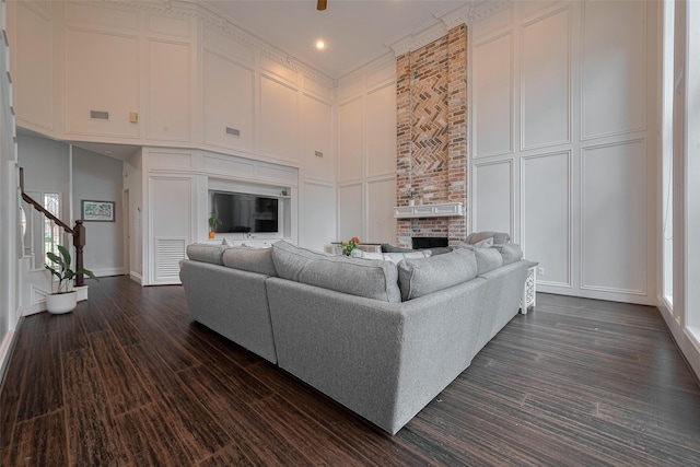 12438 Piping Rock Dr, Houston, TX 77077 - living room featuring a decorative wall, a large fireplace, dark wood finished floors, a towering ceiling, and stairway
