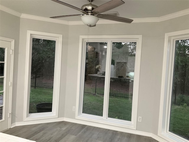 doorway with wood finished floors, ceiling fan, ornamental molding, and baseboards