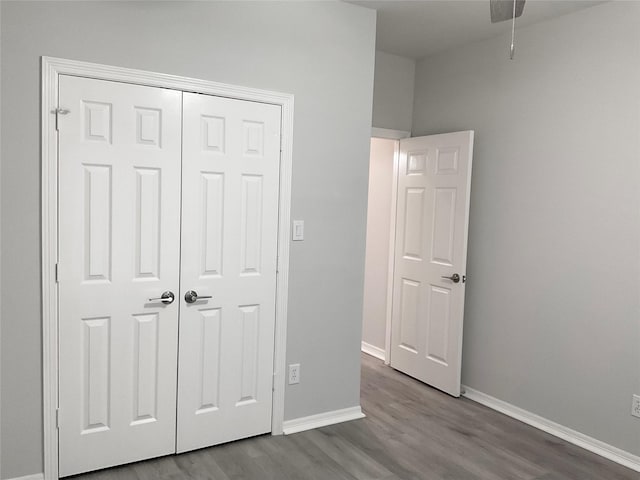 unfurnished bedroom with dark wood-type flooring, baseboards, and a closet