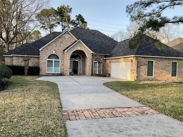 french country inspired facade featuring concrete driveway, a shingled roof, brick siding, a front lawn, and an attached garage