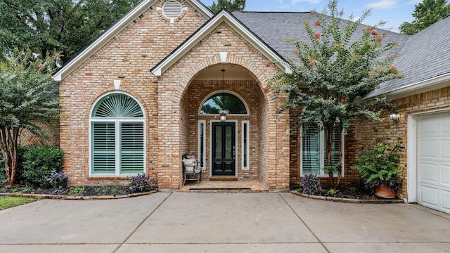 25818 Overlake Dr, Spring, TX 77380 - view of exterior entry with brick siding, concrete driveway, and a shingled roof