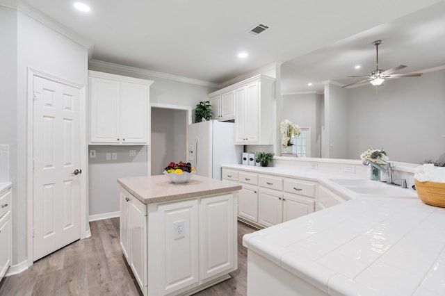 25818 Overlake Dr, Spring, TX 77380 - kitchen featuring crown molding, white refrigerator with ice dispenser, a center island, white cabinetry, and light wood-style floors