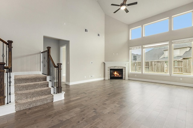 28622 Mountain Timber Ct, Fulshear, TX 77441 - unfurnished living room featuring ceiling fan, wood finished floors, high vaulted ceiling, stairway, and a glass covered fireplace