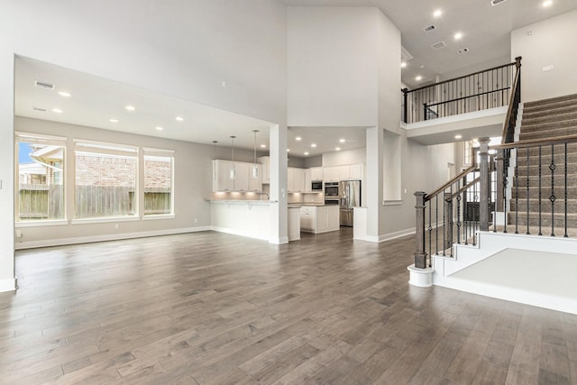 28622 Mountain Timber Ct, Fulshear, TX 77441 - unfurnished living room featuring dark wood-style flooring, stairs, a high ceiling, baseboards, and recessed lighting