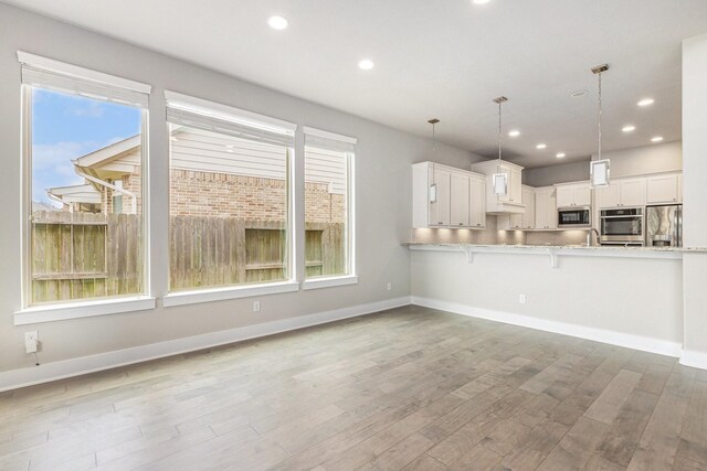 28622 Mountain Timber Ct, Fulshear, TX 77441 - kitchen featuring stainless steel fridge, built in microwave, a kitchen breakfast bar, wood finished floors, and light countertops