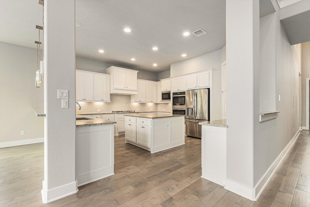 28622 Mountain Timber Ct, Fulshear, TX 77441 - kitchen featuring appliances with stainless steel finishes, a sink, recessed lighting, wood finished floors, and white cabinets