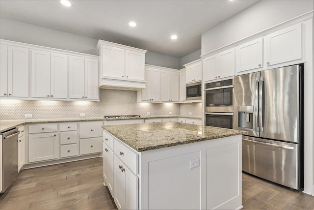 28622 Mountain Timber Ct, Fulshear, TX 77441 - kitchen featuring appliances with stainless steel finishes, white cabinetry, wood finished floors, a kitchen island, and recessed lighting