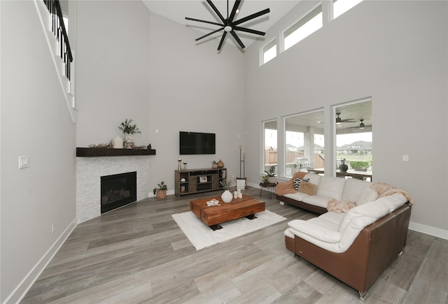 413 Stratus View Ct, Katy, TX 77493 - living area featuring a towering ceiling, plenty of natural light, a ceiling fan, a stone fireplace, and wood finished floors