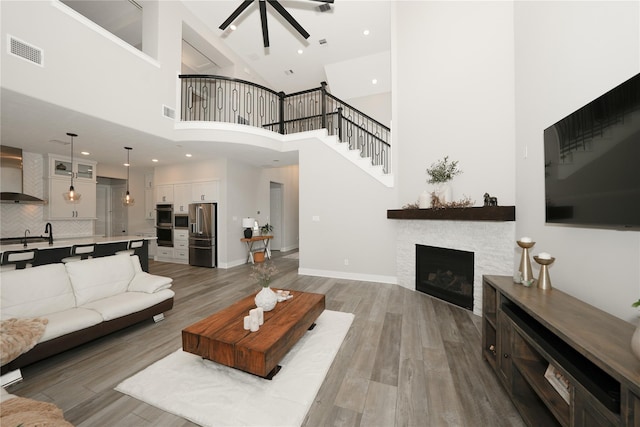 413 Stratus View Ct, Katy, TX 77493 - living room with ceiling fan, light wood finished floors, a stone fireplace, a towering ceiling, and recessed lighting