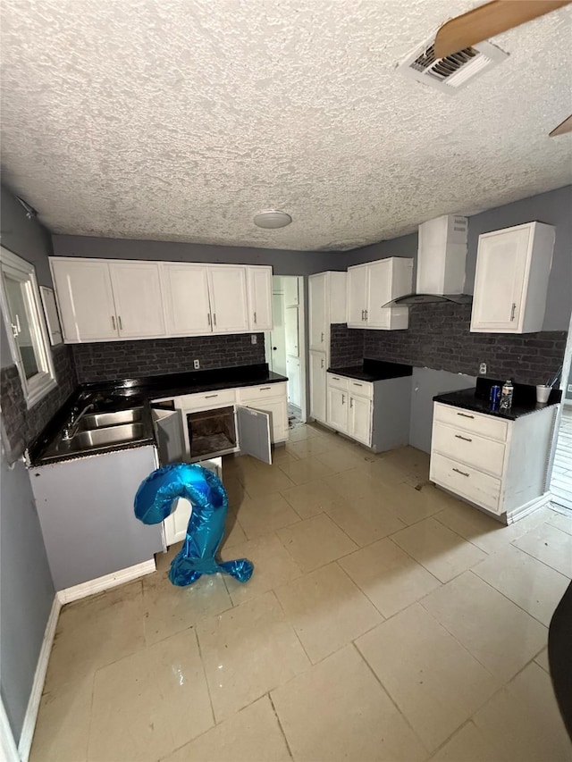 10211 Glenmawr Dr, Houston, TX 77075 - kitchen featuring wall chimney exhaust hood, backsplash, a sink, white cabinets, and a textured ceiling