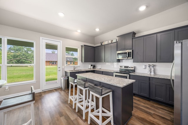 26579 Pin Oak Dr, Hempstead, TX 77445 - kitchen featuring appliances with stainless steel finishes, a sink, a kitchen island, light stone countertops, and a kitchen breakfast bar