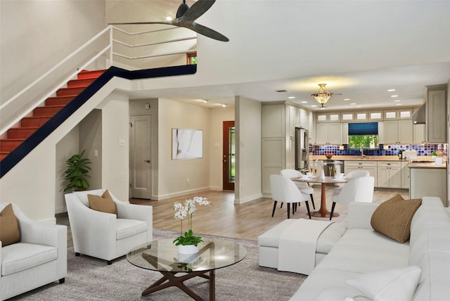 living area with stairs, recessed lighting, ceiling fan, light wood-type flooring, and baseboards