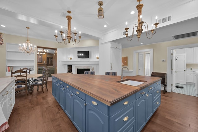 11774 Quail Creek Dr, Houston, TX 77070 - kitchen featuring wooden counters, blue cabinetry, a chandelier, a sink, and dark wood-style floors
