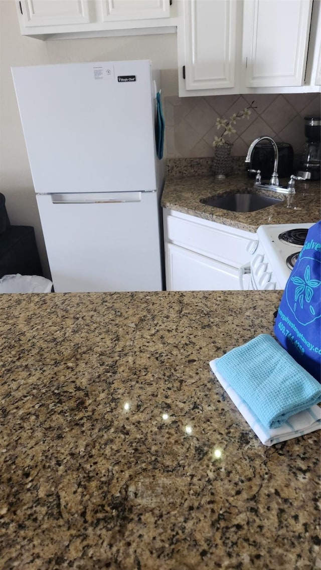 6102 Seawall Blvd Unit 358, Galveston, TX 77551 - kitchen with white appliances, a sink, white cabinets, decorative backsplash, and stone countertops