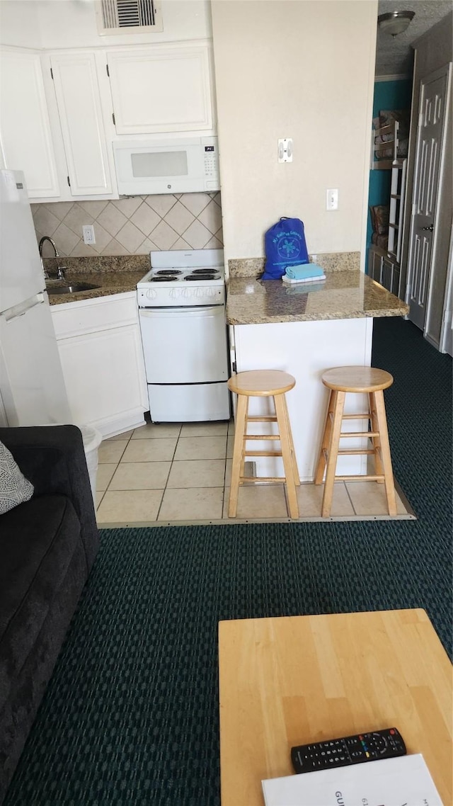 6102 Seawall Blvd Unit 358, Galveston, TX 77551 - kitchen with white appliances, white cabinets, a sink, a peninsula, and backsplash