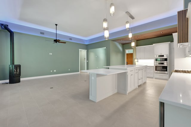 777 S Cape Royale Dr, Coldspring, TX 77331 - kitchen featuring a raised ceiling, stainless steel double oven, a sink, ceiling fan, and light countertops