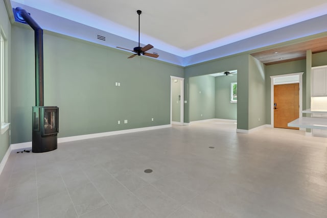 777 S Cape Royale Dr, Coldspring, TX 77331 - unfurnished living room with a ceiling fan, a wood stove, baseboards, and a raised ceiling