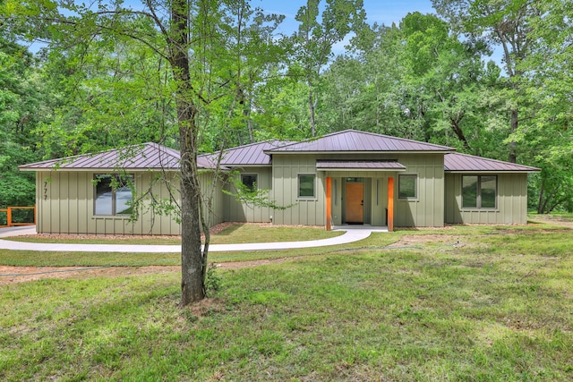 777 S Cape Royale Dr, Coldspring, TX 77331 - view of front of home with board and batten siding, a front yard, and metal roof