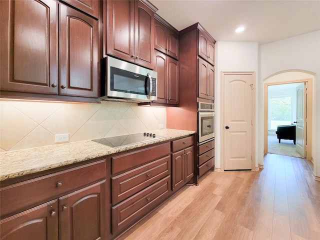 2755 Overlook Rd, Caldwell, TX 77836 - kitchen with stainless steel appliances, arched walkways, light wood-style flooring, tasteful backsplash, and light stone countertops